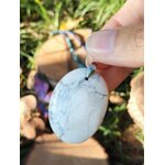 Pendentif howlite blanche tenu dans la main, pierre naturelle pour lâcher-prise, douceur du cœur et état d’esprit plus posé