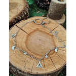 Chaîne de pantalon personnalisable argentée avec breloques lune, étoile et triangles, disposée en cercle sur rondin de bois, création Magic Gaïa