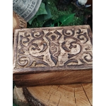 Boîte à bijoux en bois sculpté motif déesse, posée sur une tranche de bois avec du feuillage vert en arrière-plan, pour ranger bijoux et petites pierres.