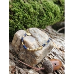 Bracelet chaîne fine dorée avec pierre naturelle bleue (lapis lazuli), posé sur mousse et bois en Bretagne