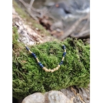 Bracelet chaîne fine dorée avec pierre naturelle bleue (lapis lazuli), posé sur mousse et bois