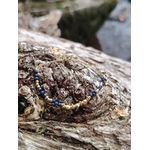 Bracelet chaîne fine doré acier inoxydable avec perles de lapis-lazuli sur bois brut, photo en extérieur Bretagne