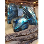 Trio de labradorites forme libre posé sur un rondin de bois brut avec guirlande lumineuse, pierres naturelles évoquant la protection, la force calme et l’enracinement intérieur.