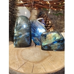 Labradorites forme libre aux reflets bleu électrique présentées sur tranche de bois, pierres naturelles associées à l’ancrage, à la vigilance intérieure et à la stabilité émotionnelle.