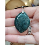 Pendentif agate mousse (goutte) sur cordon noir, sur tranche de bois avec feuillage ; apporte calme et équilibre.