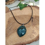 Pendentif agate mousse (goutte) sur cordon noir, posé sur tranche de bois avec feuille verte ; aide à se recentrer, apaiser et renforcer le lien à la nature.