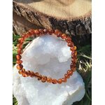 Bracelet ambre sur tranche de bois avec feuille verte et amas de quartz, ancrage lumineux, détente et sensation de cocon