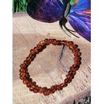 Bracelet en ambre posé près d’un papillon dans une ambiance zen, harmonie intérieure, douceur affective et tensions relâchées