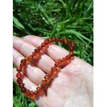 Bracelet d’ambre dans la main avec arrière-plan verdoyant, soutien émotionnel, détente nerveuse et humeur plus stable