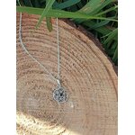Pendentif Fleur de Vie argent 925 avec perle d’ambre suspendu sur rondin de bois et feuillage, harmonie naturelle et énergie positive