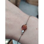 Bracelet ambre miel porté au poignet, chaîne fine en argent 925 rhodié avec cabochon rond, élégance lumineuse, détente émotionnelle et chaleur réconfortante.