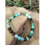 Bracelet chrysoprase posé sur planche en bois avec herbes et terre, pierre naturelle pour relâchement du mental et paix intérieure
