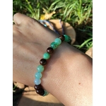 Bracelet chrysoprase porté au poignet, perles vertes et marron dans un décor d’herbes hautes et de feuilles, apaisement affectif et renouveau intérieur