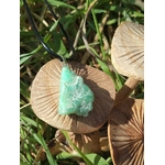 Pendentif chrysoprase brute vert d’eau posé sur tranche de bois avec herbes vertes, pierre naturelle associée au relâchement, à la paix du mental et à la souplesse émotionnelle.