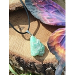 Pendentif chrysoprase pierre fine verte brute sur rondin de bois avec herbe au premier plan, bijou naturel évoquant la prise de recul, la lucidité douce et l’équilibre émotionnel.