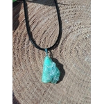 Pendentif chrysoprase naturelle brute sur cordon noir, posé sur bois aux veines marquées, bijou en pierre naturelle lié à la sensibilité apaisée, à l’harmonie du cœur et au réconfort intérieur.