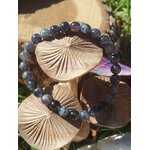 Bracelet iolite en gros plan sur décor forestier avec champignons en bois, nuances bleu-violet et gris ardoise pour stabilité mentale et respiration intérieure
