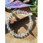 Bracelet pierre naturelle cristal de roche 6 mm posé sur bois en ambiance solaire, purification énergétique et sensation de fraîcheur intérieure