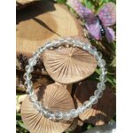 Bracelet cristal de roche 6 mm en gros plan sur fond champignons en bois, perles translucides polies pour amplification des intentions et lucidité