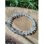 Bracelet lithothérapie cristal de roche 6 mm sur bois clair avec ombre marquée, ambiance minimaliste pour concentration et discipline mentale