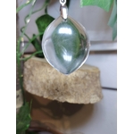 pendentif cristal de roche forme goutte en suspension, arrière-plan bois naturel et verdure, lumière douce — protection énergétique