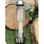 bouteille deau en verre énergisant cristal de roche, vue entière, bouchon inox avec dragonne, pointe de cristal de roche intégrée, décor rondins de bois et feuillage