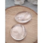 Deux galets cristal de roche polis posés sur tranche de bois en lumière naturelle, pierres translucides évoquant l’équilibre, la douceur et la clarté d’esprit.