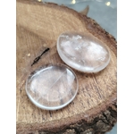 Galet cristal de roche poli tenu entre les doigts en gros plan, pierre roulée transparente avec inclusions naturelles évoquant la lucidité, le recentrage et la paix du mental.