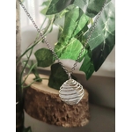 Pendentif cage spirale avec quartz blanc (cristal de roche), suspendu sur petit support en bois, décor plante verte, énergie de clarté.