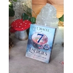 L’Oracle des 7 Énergies – coffret divinatoire en français, boîte posée sur surface grise avec décor nature (champignon décoratif rouge, feuillage) et pierre blanche en arrière-plan.