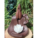 Porte-encens backflow Mains Lotus en terre cuite brun foncé, vue de face, posé sur rondin de bois, décor herbe haute en extérieur.