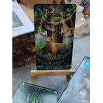 Carte du Tarot Celtique Universel sur chevalet en bois, boîtes du jeu ouvertes sur table, ambiance ésotérique