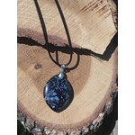 Pendentif indigo gabbro en forme de goutte sur cordon noir, présenté sur bois brut, bijou en pierre naturelle évoquant la force calme, la stabilité et les nouveaux élans.