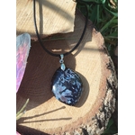 Pendentif goutte en gabbro sur cordon noir, posé sur rondin de bois avec décor ésotérique, pierre naturelle associée au recentrage, à la stabilité intérieure et à l’ancrage.