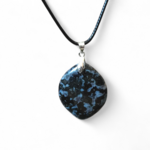 Pendentif indigo gabbro en gros plan sur fond blanc, pierre naturelle sombre aux motifs nuancés reliée à la lucidité, à la solidité émotionnelle et à la présence à soi.