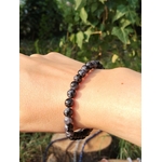 Bracelet Gabbro porté au poignet, perles bleu-noir en extérieur sur fond feuillage, bijou en pierre naturelle pour ancrage et stabilité