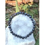Bracelet Gabbro sombre aux reflets bleutés sur pierre claire, photo nature, pierre de protection et d’ancrage