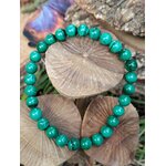 Bracelet malachite vert marbré posé sur champignons en bois, photo nature originale, bijou en pierre naturelle au rendu chaleureux.
