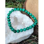 Bracelet malachite 6 mm posé sur amas de quartz blanc, contraste minéral et vert profond, protection douce et clarté émotionnelle