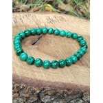 Bracelet en malachite sur rondin de bois, perles vertes veinées et fond végétal, création nature liée au calme intérieur