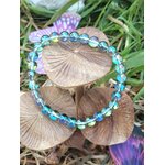 Bracelet Aqua Aura sur bois naturel avec feuillage, perles lumineuses aux reflets aqua, apaisement des pensées et retour à soi