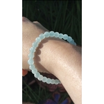 Bracelet Aigue-Marine 6 mm porté à la main, perles bleu océan en gros plan, détente intérieure et relâchement émotionnel.