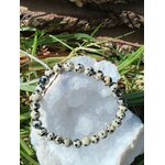 Bracelet pierre dalmatienne 6 mm sur planche en bois avec plantes vertes, perles crème sable et taches noires pour lâcher-prise et stabilité intérieure
