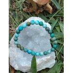Bracelet turquoise du Tibet présenté sur un amas de quartz cristallisée avec herbes et champignons, équilibre émotionnel et protection douce