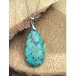 Pendentif turquoise africaine forme goutte bleu-vert sur bélière argentée, posé sur bois clair, jaspe africain associé à la douceur intérieure, à la communication apaisée et à l’harmonie émotionnelle.