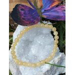 Bracelet calcite jaune posé sur géode claire avec papillon, bijou lumineux pour optimisme, stabilité émotionnelle et attention posée