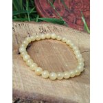 Bracelet en calcite jaune posé sur bois brut avec brins verts, bijou en pierre naturelle pour bonne humeur, élan positif et esprit plus clair