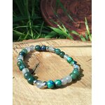 Bracelet Éveil spirituel photographié sur planche de bois avec herbes vertes et décor gravé, lucidité, enracinement et paix du mental
