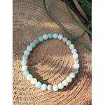 Bracelet amazonite multicolore en perles 6 mm, photographié sur bois texturé avec feuillage vert en arrière-plan ; pierre associée à l’apaisement, à l’expression et à l’équilibre émotionnel.