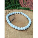 Bracelet célestine sur rondin de bois avec feuillage vert et décor en arrière-plan, perles bleu givré 6 mm, recentrage, écoute calme et expression fluide